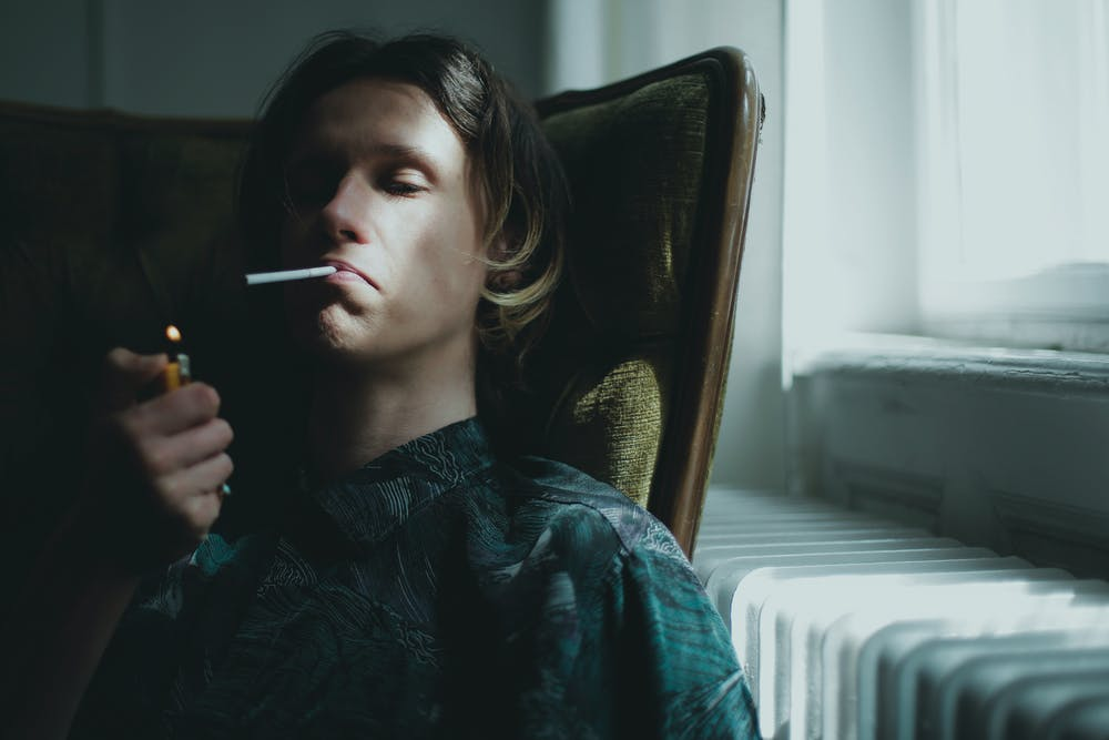 A young man lighting up cigarette.