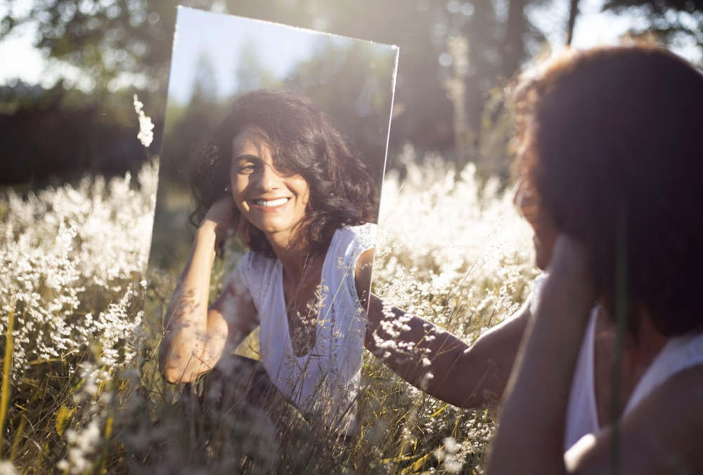 A woman smiling at her reflection in a mirror