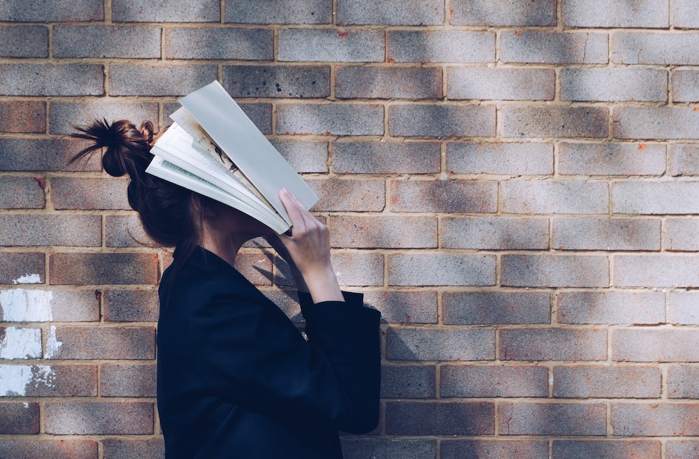 A woman covering her face with a book